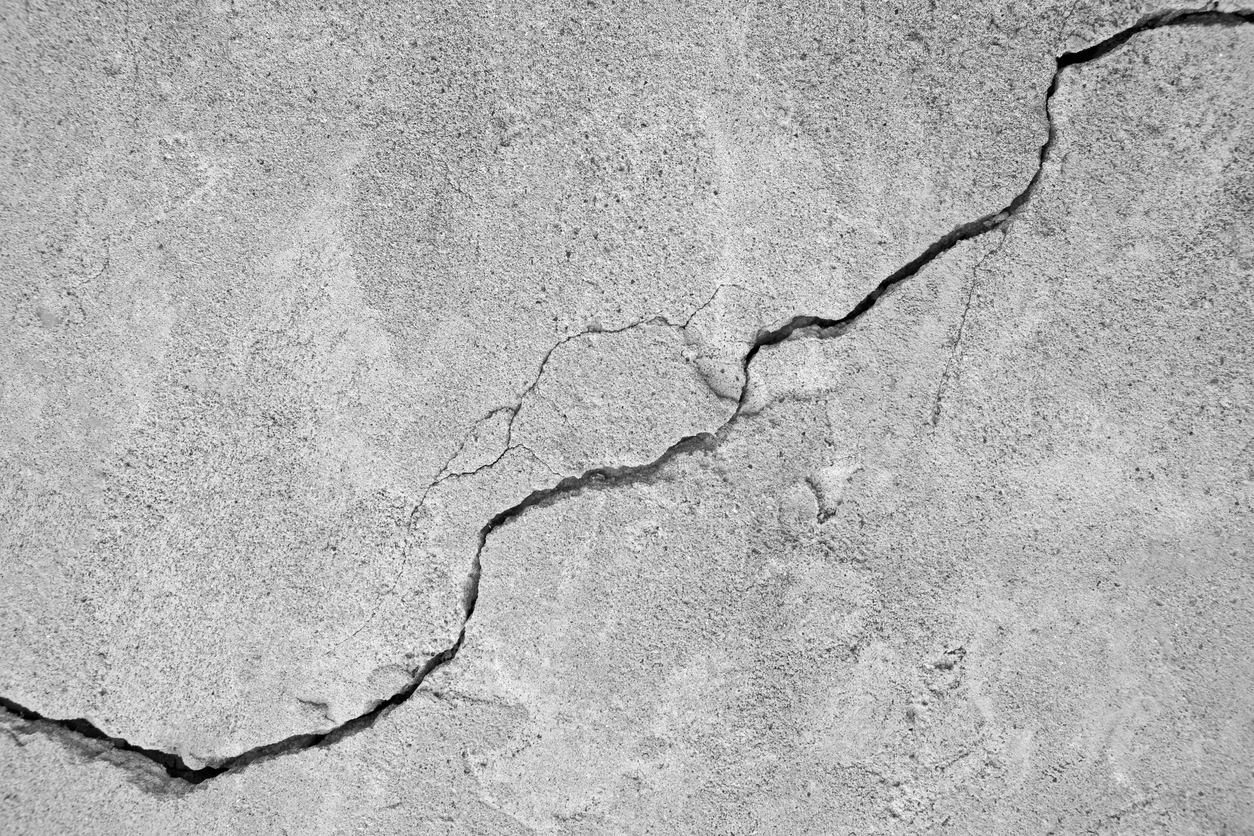 Big winding ascending crack on an gray concrete wall, thin crack diagonally. Copy space