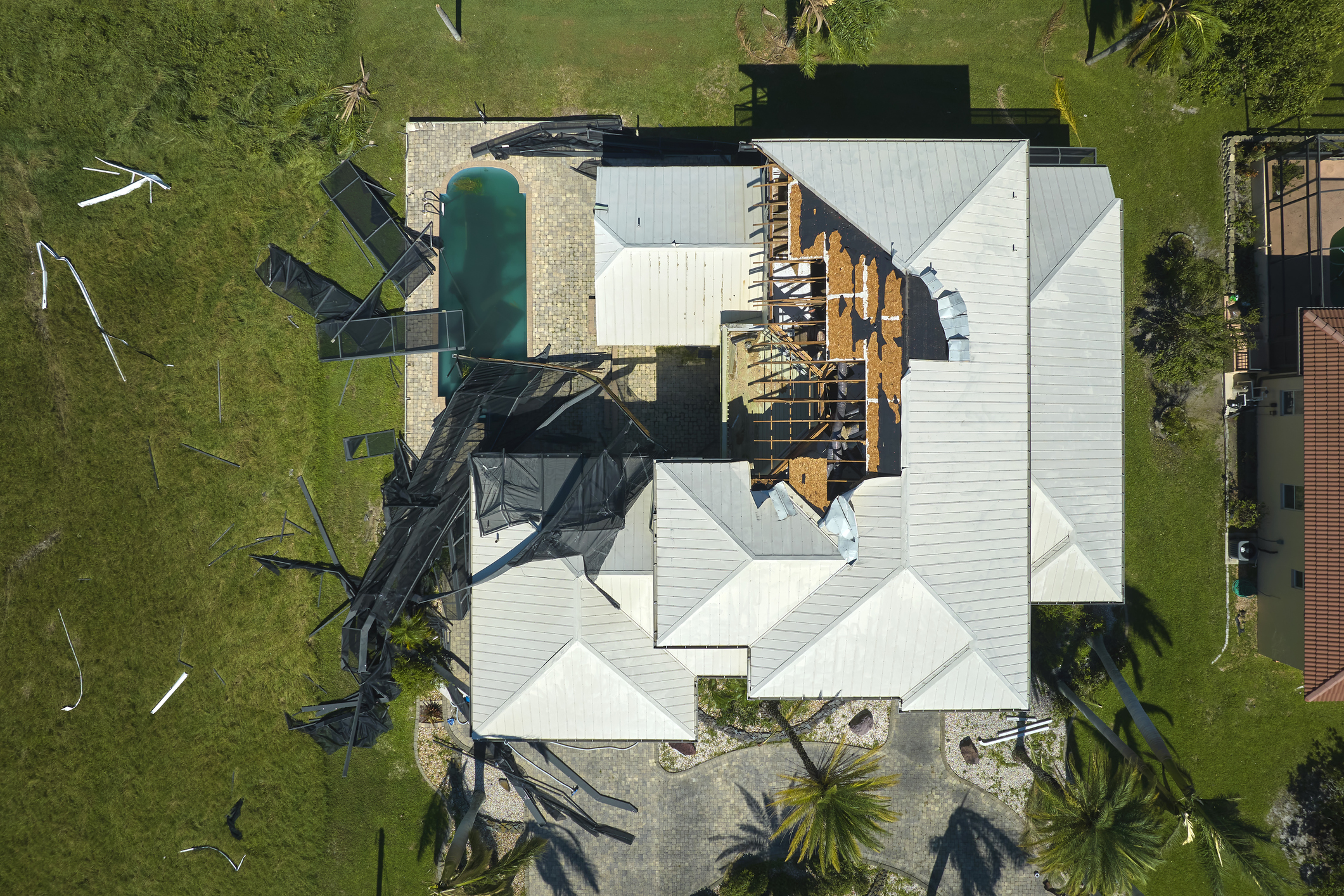 Hurricane Ian destroyed swimming pool lanai enclosure on house yard in Florida residential area